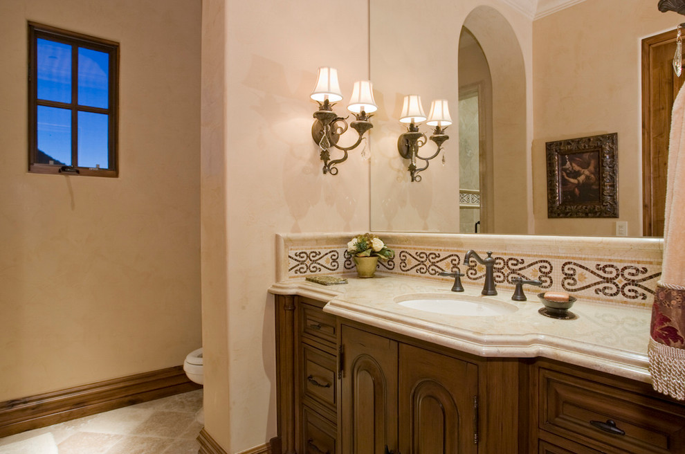 На фото: огромная ванная комната в средиземноморском стиле с фасадами островного типа, светлыми деревянными фасадами, раздельным унитазом, бежевой плиткой, плиткой мозаикой, бежевыми стенами, полом из травертина, настольной раковиной и столешницей из гранита