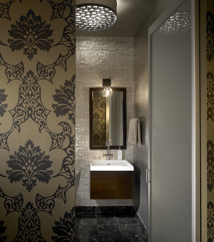 シカゴにあるインダストリアルスタイルのおしゃれなトイレ・洗面所 (壁付け型シンク、濃色木目調キャビネット、グレーのタイル、照明) の写真