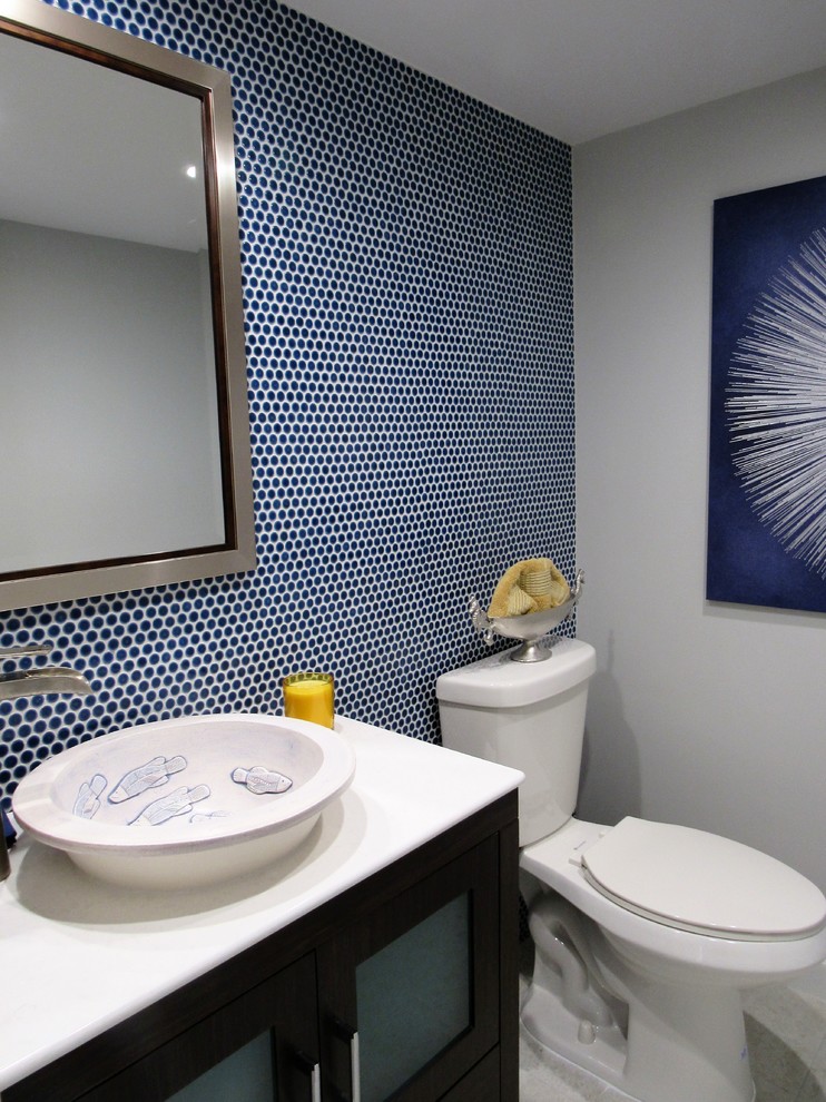 This is an example of a small classic cloakroom in Miami with glass-front cabinets, dark wood cabinets, a two-piece toilet, blue tiles, mosaic tiles, blue walls, travertine flooring, a vessel sink, solid surface worktops and beige floors.
