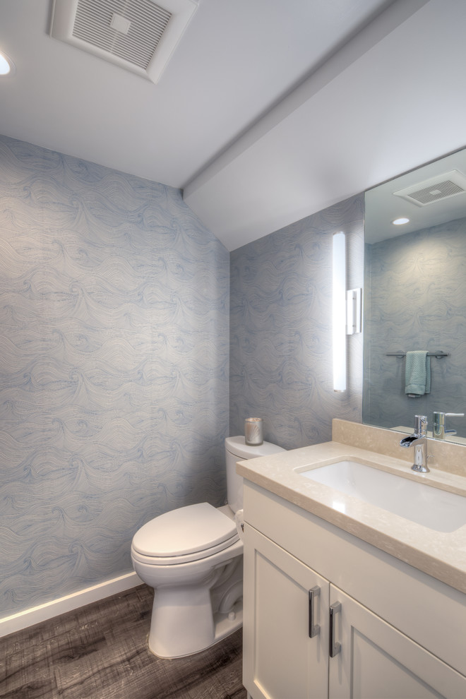 Idee per un piccolo bagno di servizio design con ante in stile shaker, ante bianche, WC monopezzo, pareti blu, lavabo sottopiano, top in quarzo composito, parquet scuro, pavimento marrone e top beige