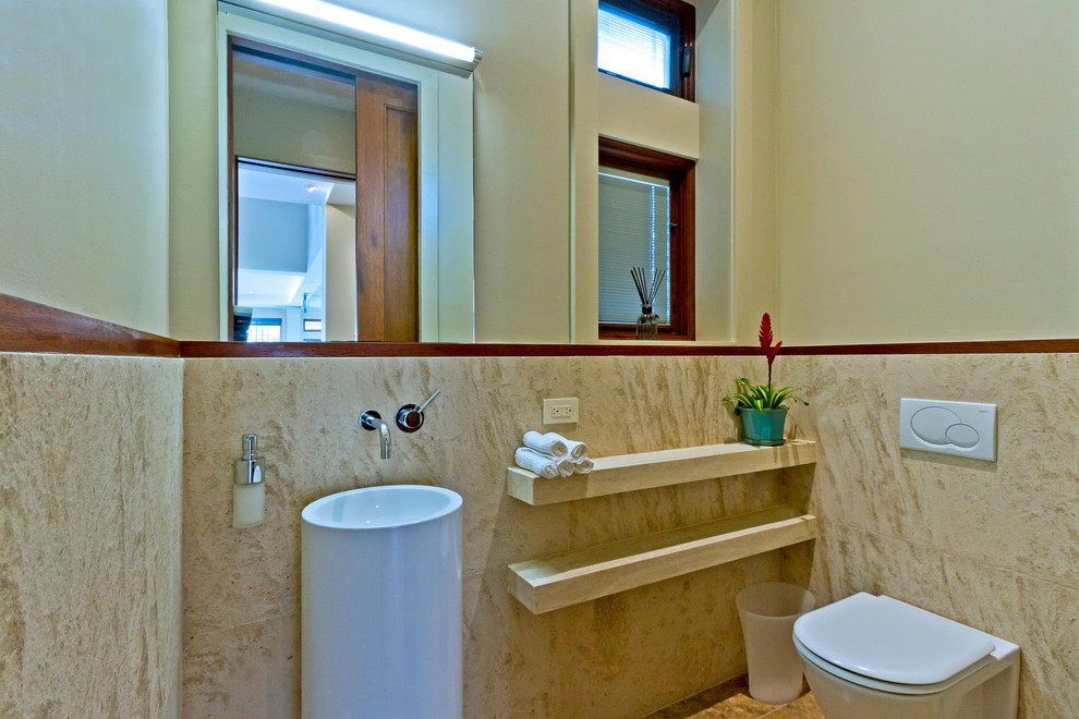 Foto på ett mellanstort funkis toalett, med öppna hyllor, en vägghängd toalettstol, beige kakel, travertinkakel, beige väggar, travertin golv, ett piedestal handfat och beiget golv