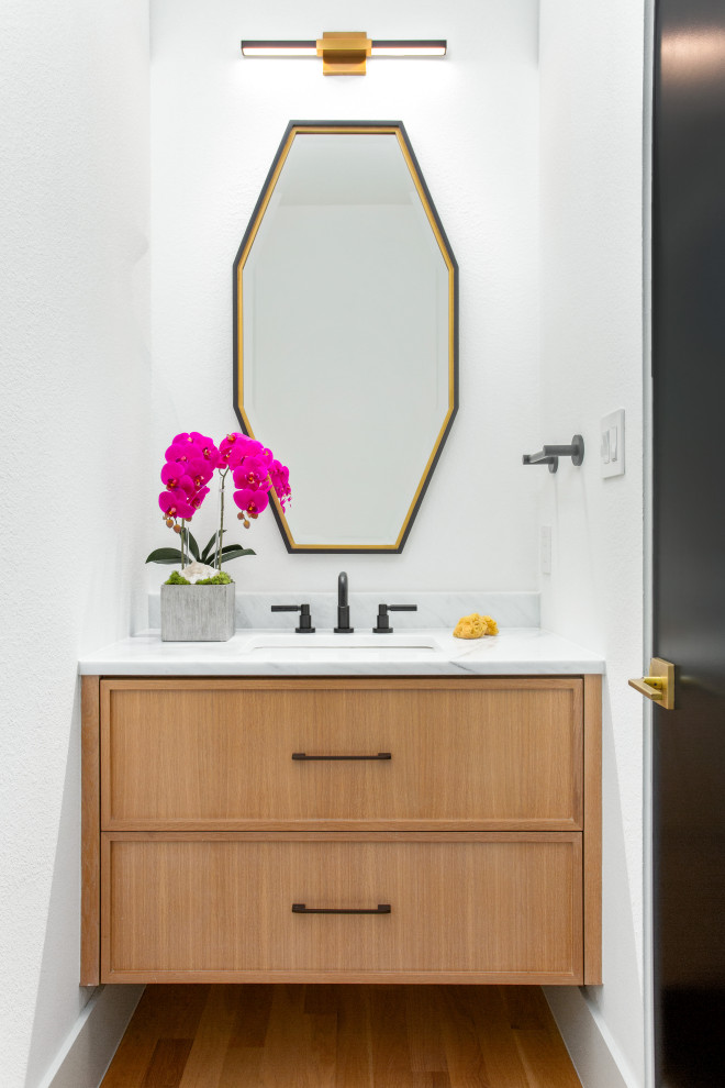 Cette image montre un WC et toilettes nordique en bois clair avec un mur blanc, parquet clair, un lavabo encastré, un plan de toilette blanc et meuble-lavabo suspendu.