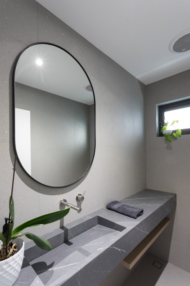 Стильный дизайн: туалет в современном стиле с серыми фасадами, серой плиткой, керамогранитной плиткой, столешницей из плитки, серой столешницей и подвесной тумбой - последний тренд
