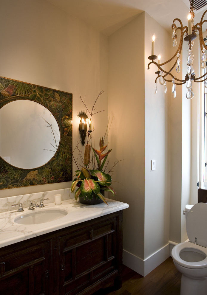 サンフランシスコにあるトロピカルスタイルのおしゃれなトイレ・洗面所 (アンダーカウンター洗面器、濃色木目調キャビネット、白い洗面カウンター) の写真