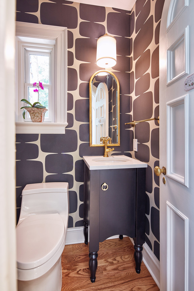 Klassisk inredning av ett litet vit vitt toalett, med möbel-liknande, svarta skåp, en toalettstol med hel cisternkåpa, svarta väggar, ett undermonterad handfat, bänkskiva i kvarts, mellanmörkt trägolv och brunt golv