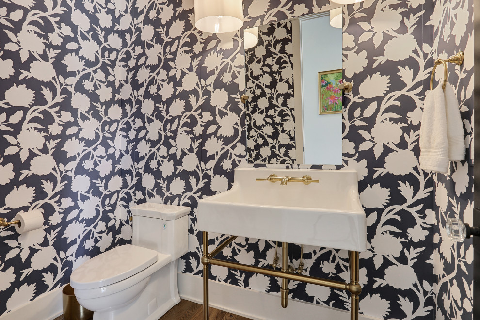 Inredning av ett klassiskt mellanstort toalett, med möbel-liknande, vita skåp, en toalettstol med hel cisternkåpa, blå väggar, mellanmörkt trägolv, ett konsol handfat och brunt golv