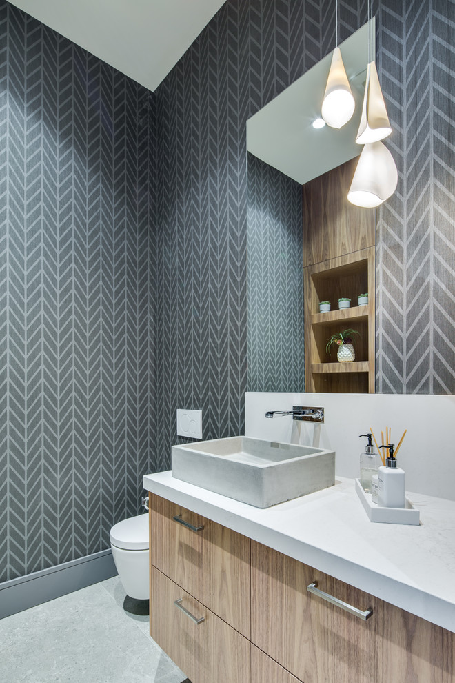 Moderne Gästetoilette mit flächenbündigen Schrankfronten, hellen Holzschränken, grauer Wandfarbe, Aufsatzwaschbecken, grauem Boden und weißer Waschtischplatte in Vancouver