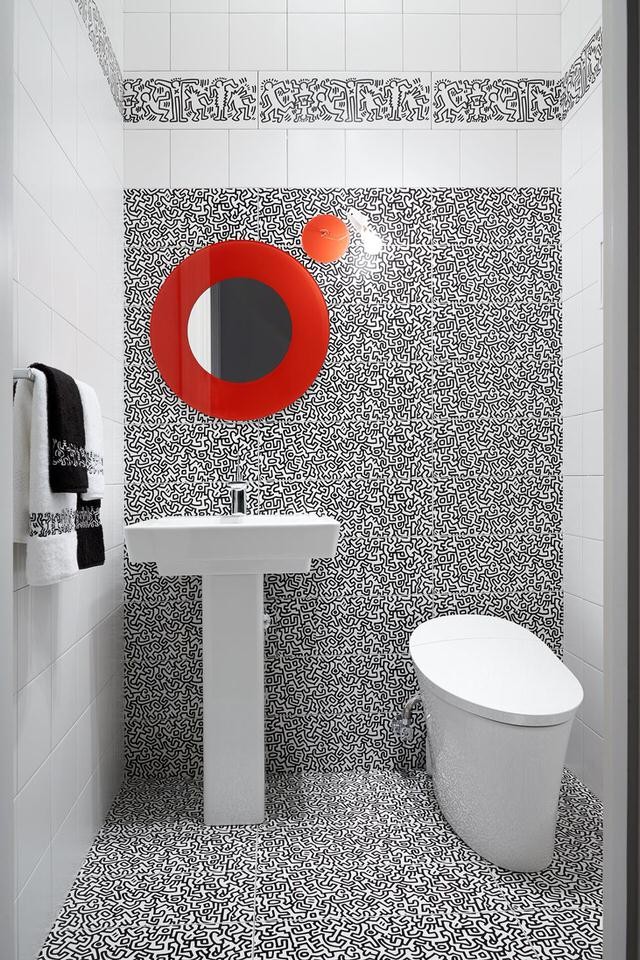 Bild på ett stort funkis toalett, med en toalettstol med hel cisternkåpa, svart och vit kakel, vit kakel, keramikplattor, vita väggar, klinkergolv i keramik och ett piedestal handfat