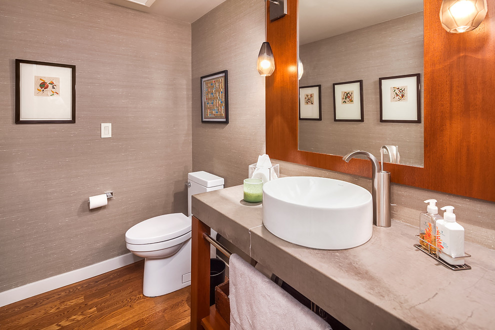 Exempel på ett litet modernt toalett, med släta luckor, skåp i mellenmörkt trä, en toalettstol med hel cisternkåpa, grå väggar, mellanmörkt trägolv, ett piedestal handfat och bänkskiva i kalksten