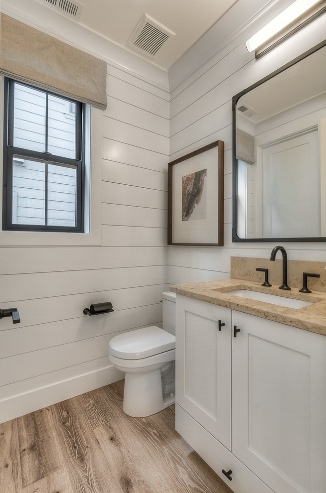 Klassische Gästetoilette mit Schrankfronten mit vertiefter Füllung, weißen Schränken, weißer Wandfarbe und hellem Holzboden in Seattle