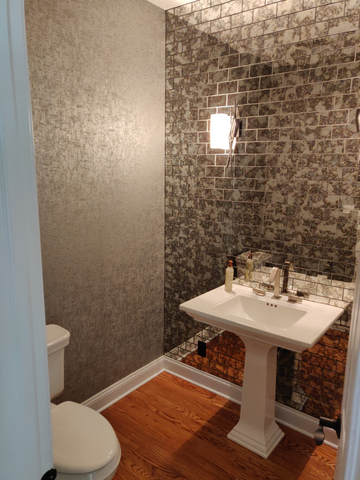 Large modern cloakroom in Philadelphia with a two-piece toilet, glass tiles, grey walls, medium hardwood flooring and a pedestal sink.