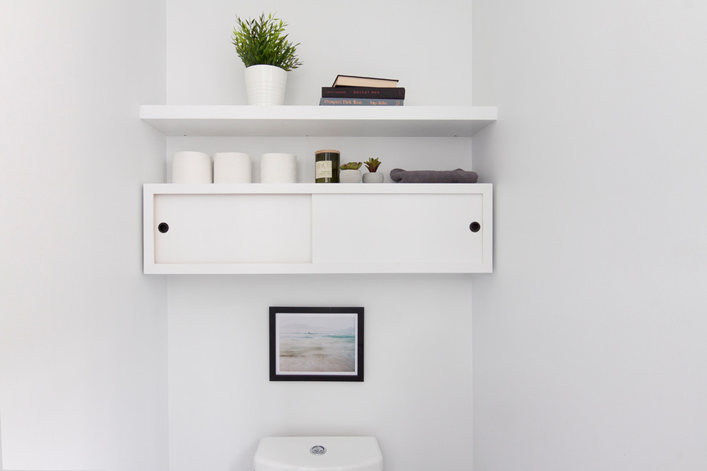 This is an example of a small scandinavian cloakroom in New York with flat-panel cabinets, white cabinets, a two-piece toilet, white walls, porcelain flooring, a pedestal sink and grey floors.