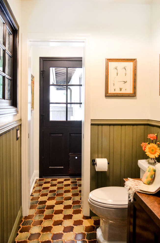 Пример оригинального дизайна: маленький туалет в средиземноморском стиле с фасадами островного типа, темными деревянными фасадами, унитазом-моноблоком, зеленой плиткой, белыми стенами, полом из керамической плитки, настольной раковиной, столешницей из меди, разноцветным полом и коричневой столешницей для на участке и в саду