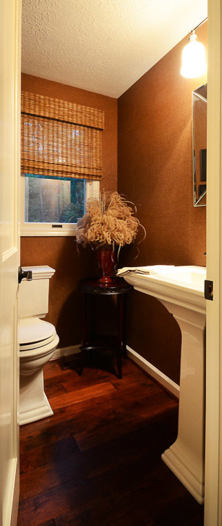 Photo of a medium sized traditional cloakroom in New York with a two-piece toilet, brown walls, dark hardwood flooring, a pedestal sink and brown floors.