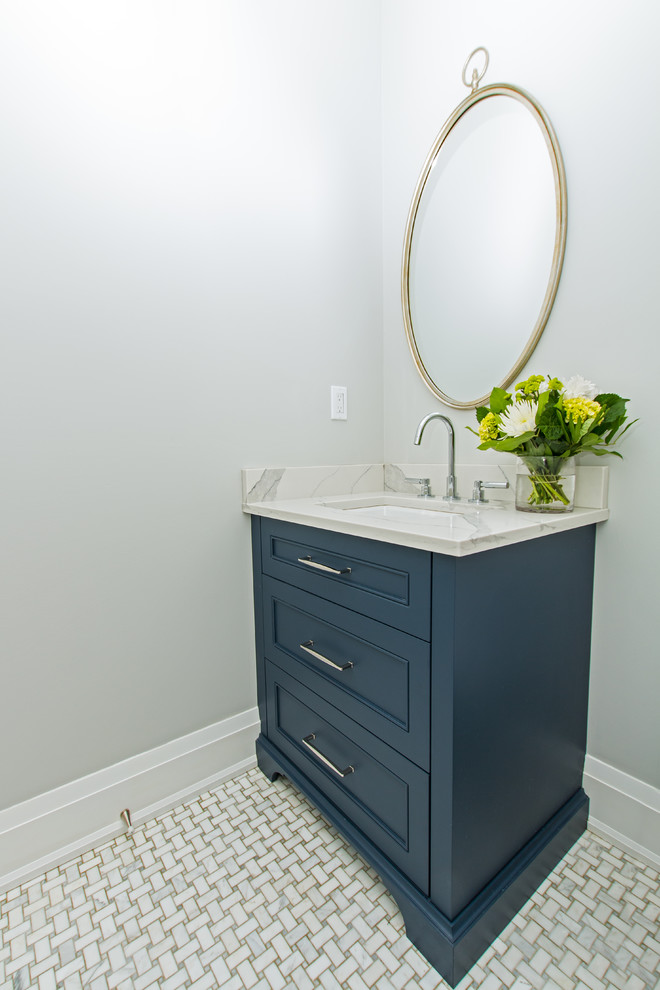 Klassisk inredning av ett mellanstort vit vitt toalett, med luckor med infälld panel, blå skåp, en toalettstol med hel cisternkåpa, grå väggar, marmorgolv, ett undermonterad handfat, marmorbänkskiva och grått golv