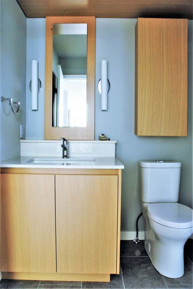 Idéer för små funkis vitt toaletter, med släta luckor, bruna skåp, en toalettstol med separat cisternkåpa, blå väggar, klinkergolv i porslin, ett undermonterad handfat, bänkskiva i kvarts och grått golv