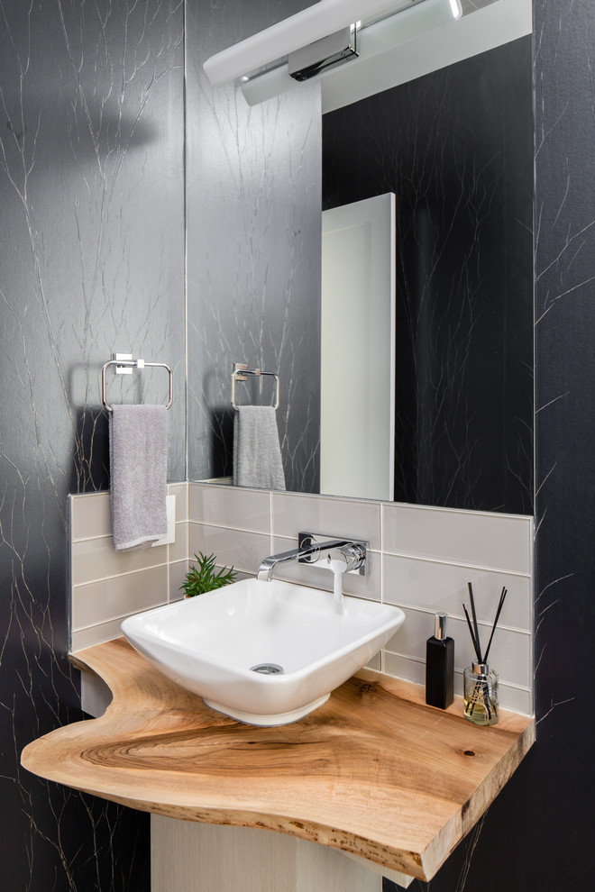 Inspiration pour un WC et toilettes traditionnel avec un carrelage gris, un carrelage métro, un mur noir, une vasque et un plan de toilette en bois.