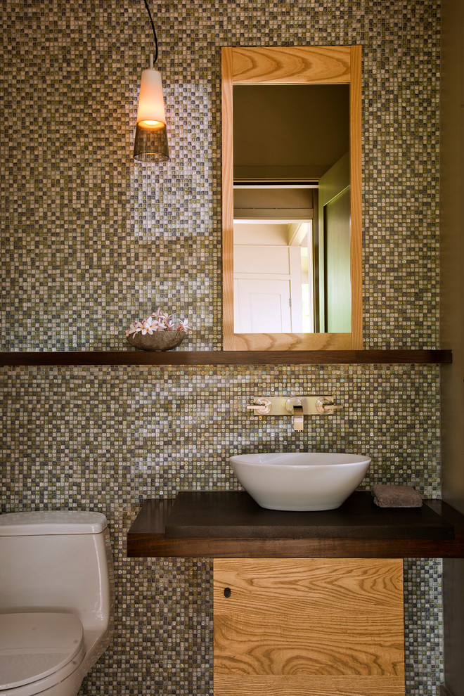 Immagine di un bagno di servizio tropicale con lavabo a bacinella, piastrelle verdi, piastrelle a mosaico e top marrone