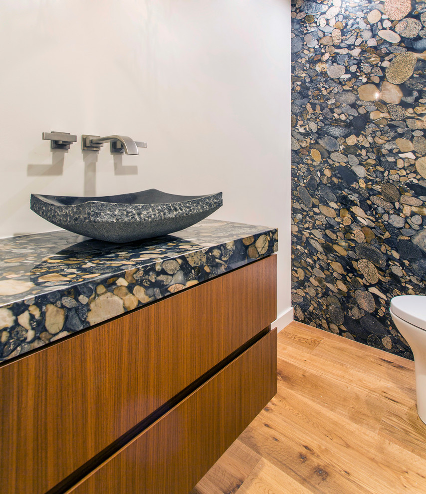 Cette photo montre un WC et toilettes tendance en bois brun de taille moyenne avec un placard à porte plane, un carrelage multicolore, des dalles de pierre, un mur blanc, un sol en bois brun, une vasque, un plan de toilette en granite, un sol marron et un plan de toilette multicolore.