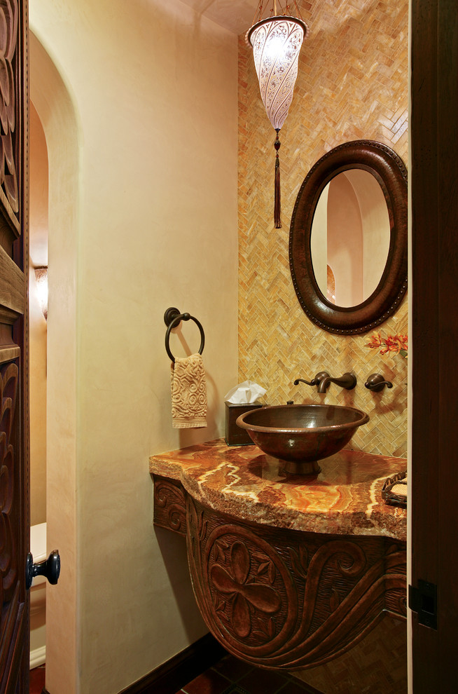 Example of a tuscan beige tile powder room design in San Diego with a vessel sink, furniture-like cabinets, dark wood cabinets and beige walls