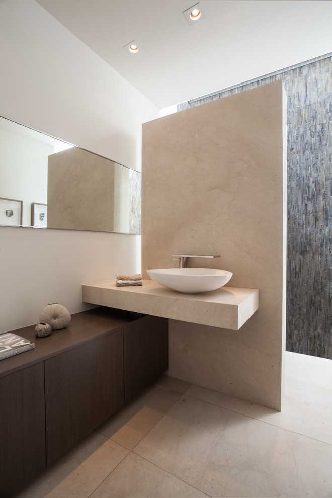 Expansive contemporary cloakroom in Orange County with a vessel sink, freestanding cabinets, dark wood cabinets, limestone worktops, beige tiles, matchstick tiles, white walls, travertine flooring and beige worktops.