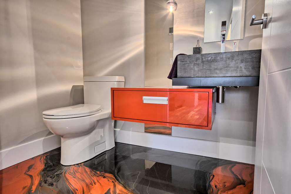 Immagine di un piccolo bagno di servizio design con ante lisce, ante rosse, WC monopezzo, pareti grigie, pavimento in cemento, lavabo sospeso, top in superficie solida e pavimento rosso