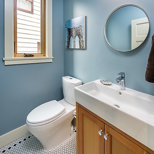Example of a mid-sized transitional white tile and porcelain tile mosaic tile floor and white floor powder room design in Portland with shaker cabinets, medium tone wood cabinets, blue walls, a trough sink, solid surface countertops and a two-piece toilet