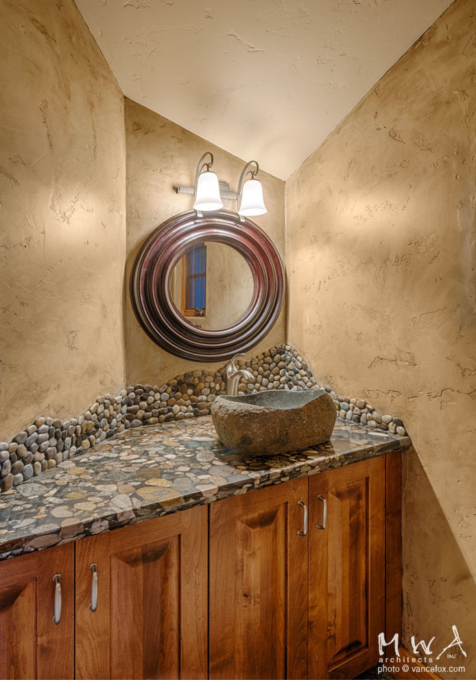Inspiration for a mid-sized rustic pebble tile powder room remodel in Sacramento with a vessel sink, raised-panel cabinets, medium tone wood cabinets and beige walls