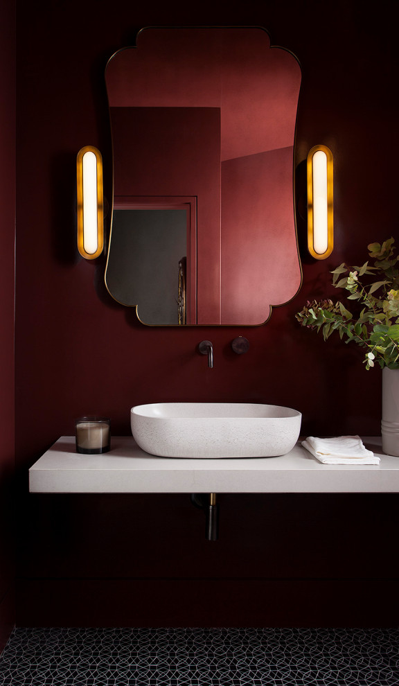 На фото: туалет в современном стиле с красными стенами, настольной раковиной, черным полом и белой столешницей