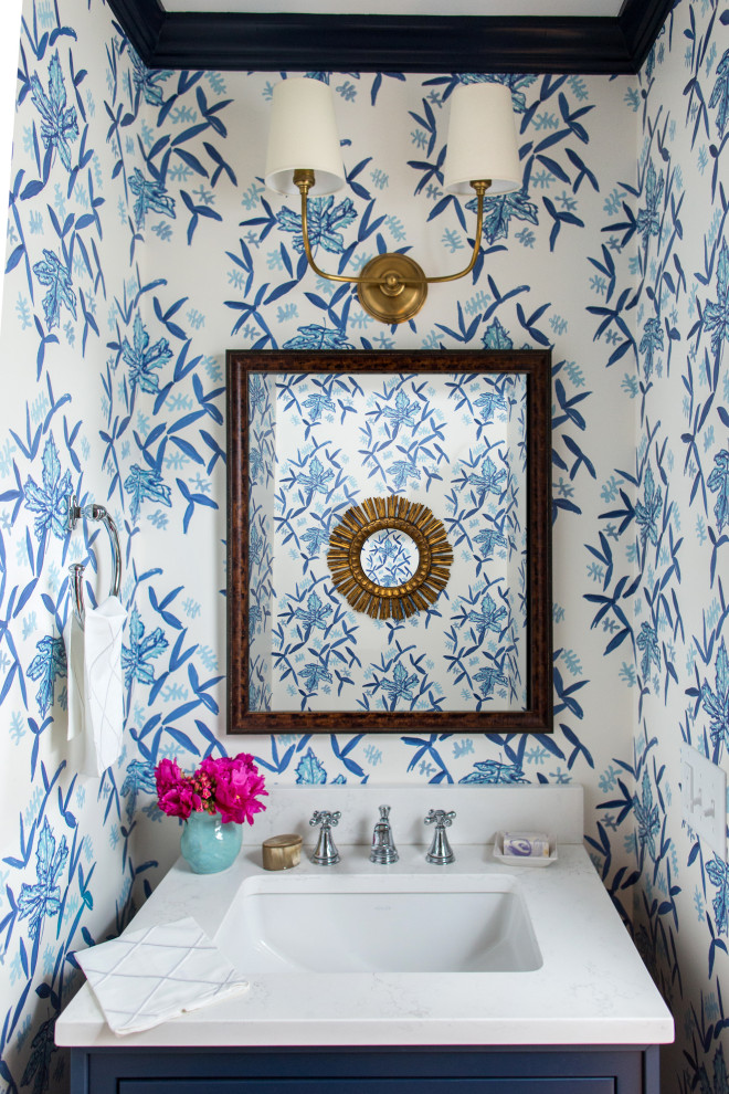 Klassisk inredning av ett litet vit vitt toalett, med släta luckor, blå skåp, flerfärgade väggar och ett undermonterad handfat