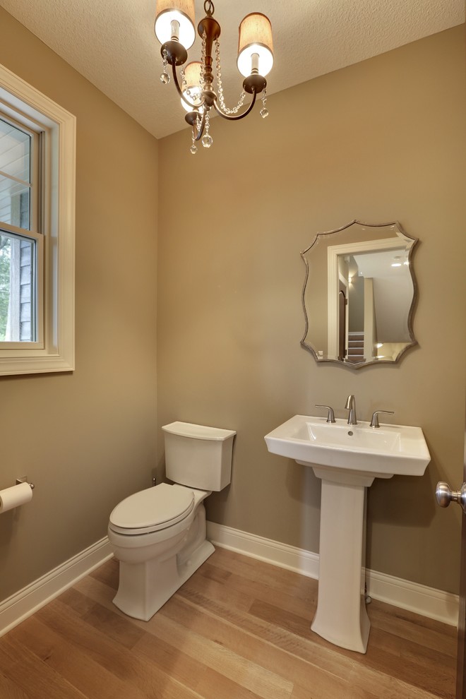 Inspiration for a medium sized classic cloakroom in Minneapolis with a pedestal sink, a two-piece toilet, grey walls and light hardwood flooring.