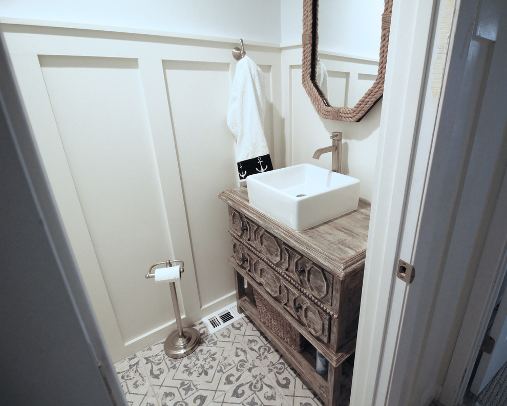 Design ideas for a small coastal cloakroom in Austin with freestanding cabinets, medium wood cabinets, white walls, a vessel sink, wooden worktops, beige floors and brown worktops.