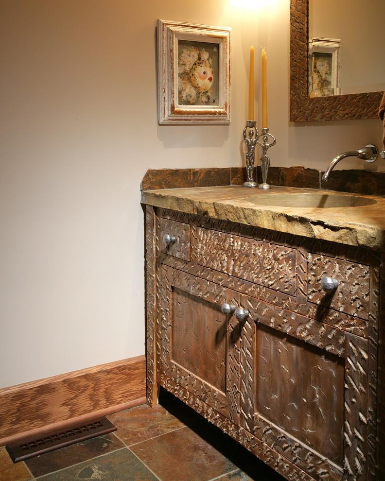 Modelo de aseo tradicional pequeño con armarios tipo mueble, puertas de armario de madera en tonos medios, paredes beige, suelo de pizarra y lavabo integrado