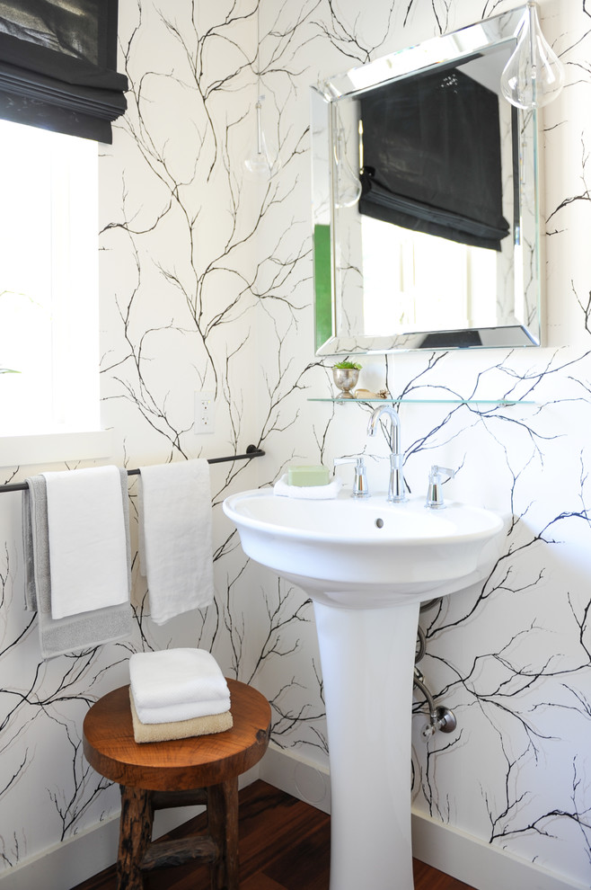 Imagen de aseo costero de tamaño medio con lavabo con pedestal, suelo de madera en tonos medios y paredes blancas
