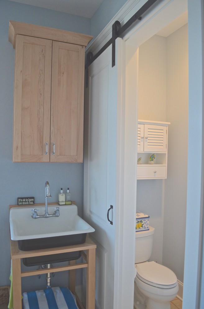 Bild på ett maritimt toalett, med skåp i ljust trä, blå väggar, klinkergolv i porslin och ett konsol handfat