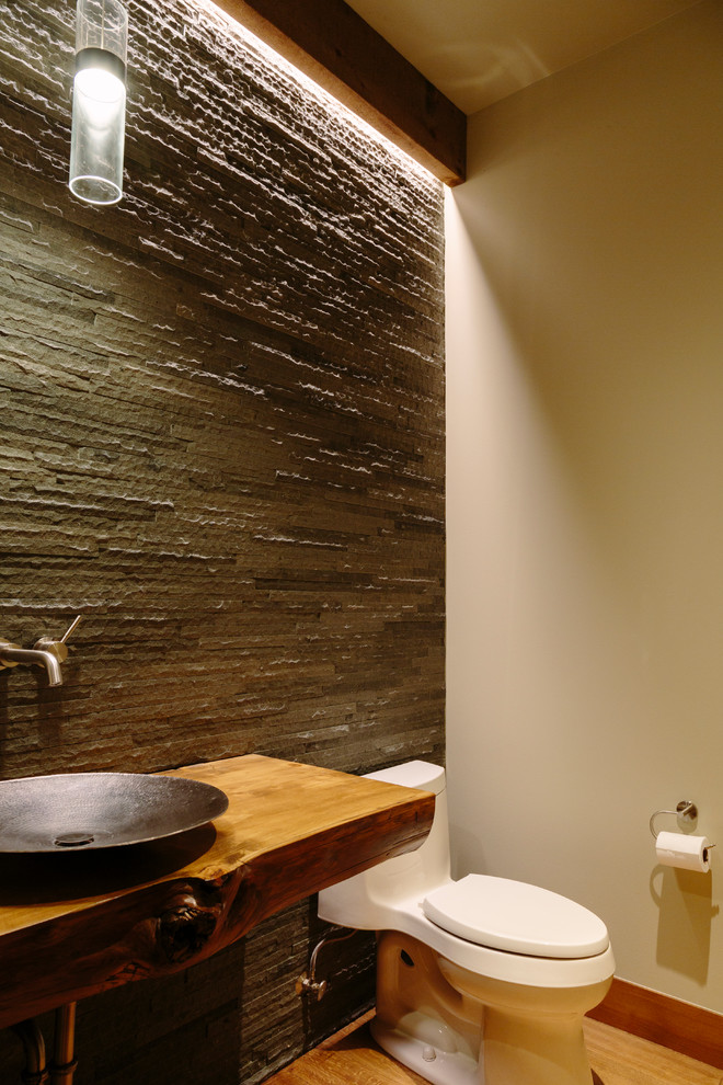 Пример оригинального дизайна: туалет среднего размера в стиле рустика с унитазом-моноблоком, серой плиткой, каменной плиткой, белыми стенами, светлым паркетным полом, настольной раковиной, столешницей из дерева и коричневой столешницей