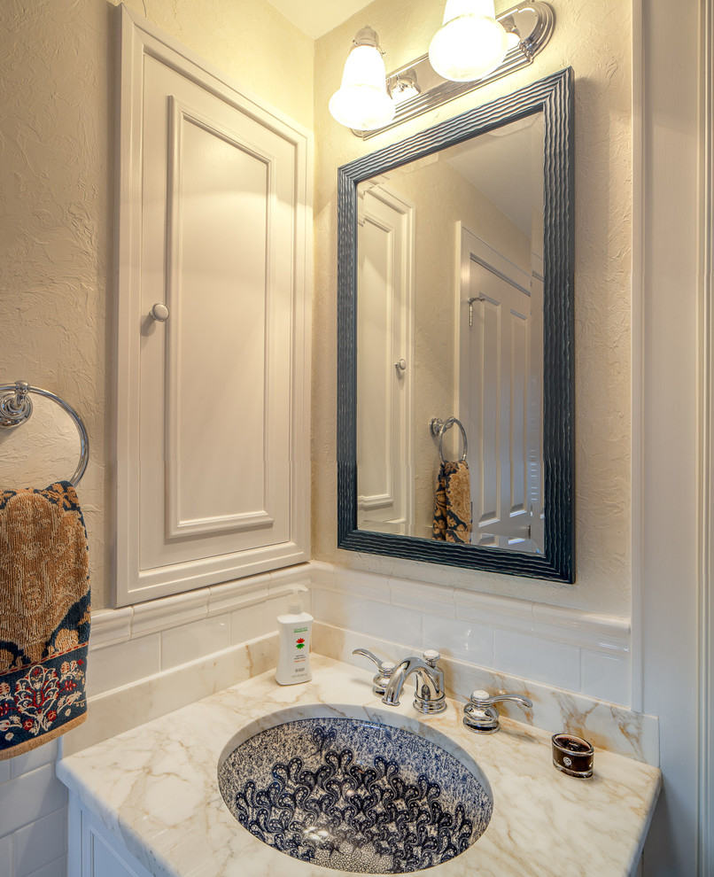 Cette image montre un WC et toilettes traditionnel avec un lavabo encastré, des portes de placard blanches, un plan de toilette en marbre, WC à poser, un carrelage blanc et un carrelage métro.
