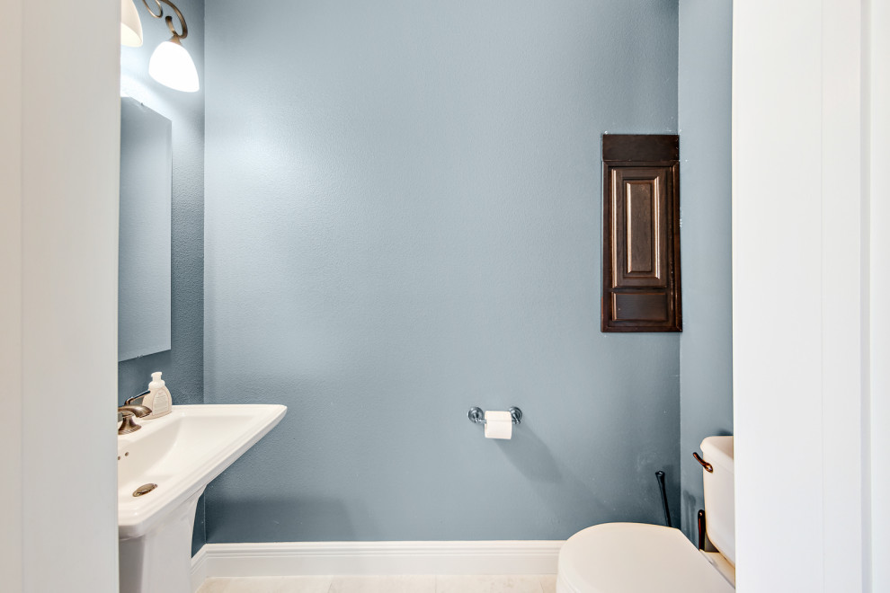 Cette photo montre un WC et toilettes bord de mer avec des portes de placard blanches, un mur bleu, un sol en carrelage de céramique et un sol beige.