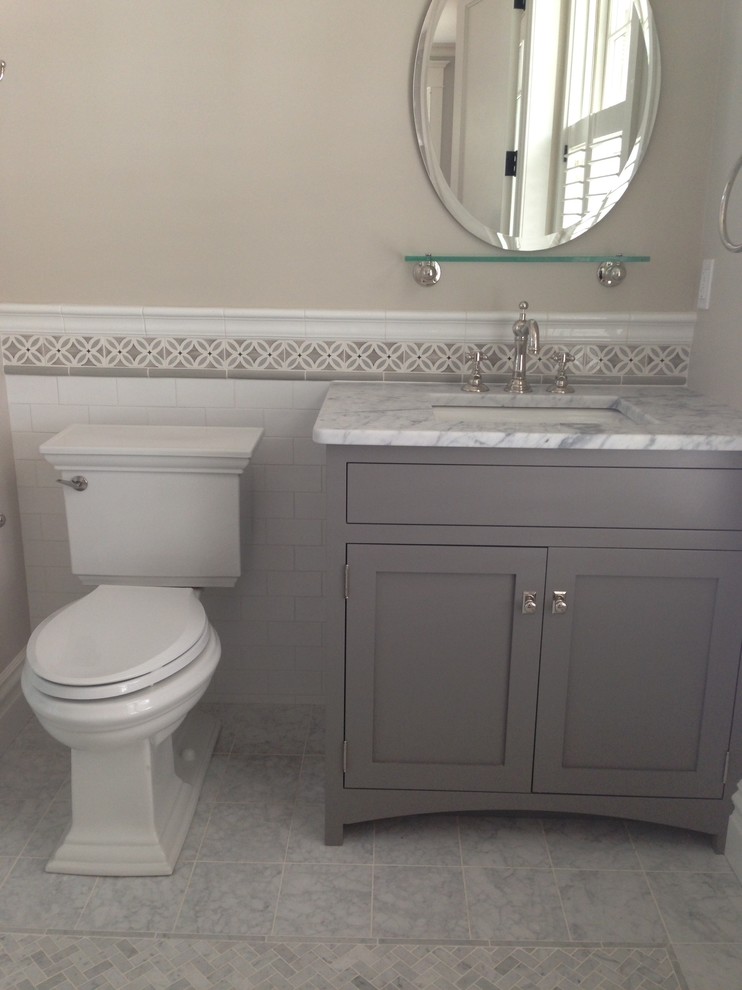 Inspiration for a medium sized country cloakroom in Portland Maine with beaded cabinets, grey cabinets, a two-piece toilet, white tiles, metro tiles, beige walls, porcelain flooring, a submerged sink, marble worktops and grey floors.