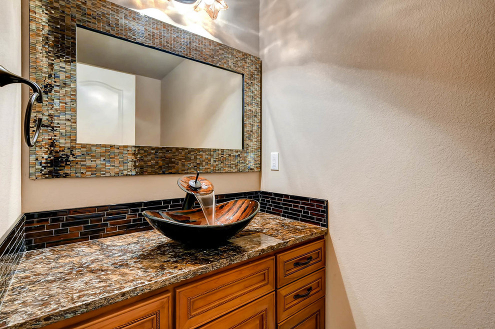 Inspiration for a mid-sized craftsman brown tile and ceramic tile powder room remodel in Denver with beaded inset cabinets, dark wood cabinets, beige walls, a vessel sink, granite countertops and brown countertops