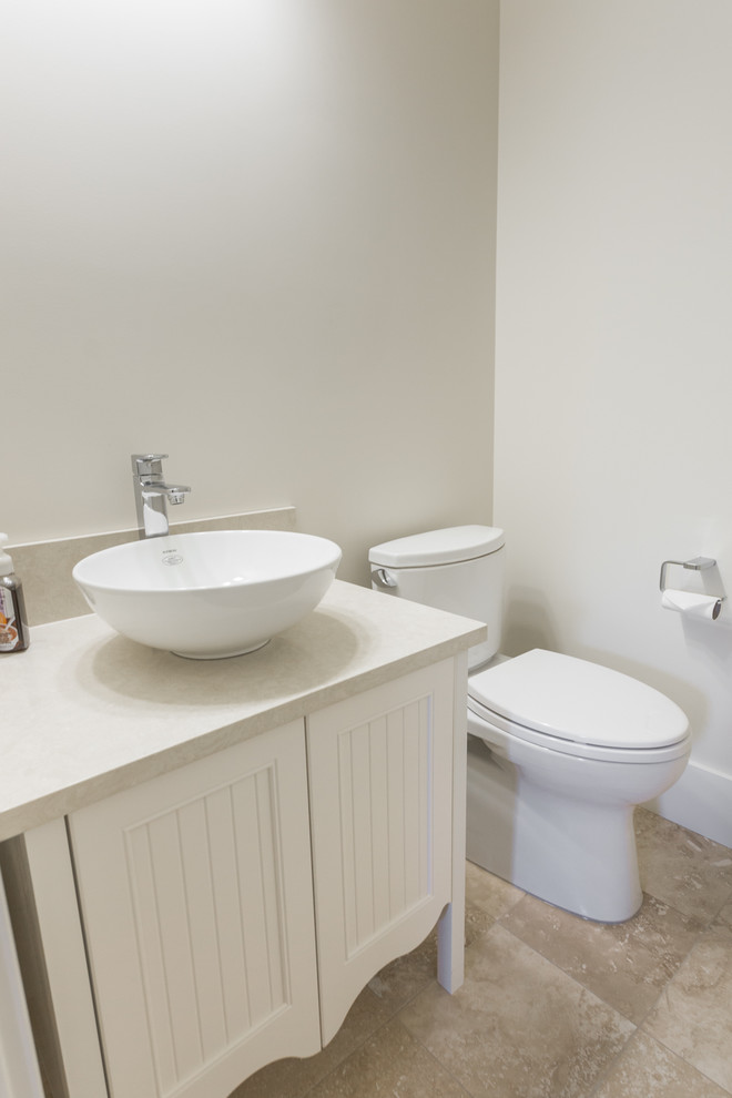 Example of a small minimalist beige floor powder room design with recessed-panel cabinets, white cabinets, a one-piece toilet, white walls and a vessel sink