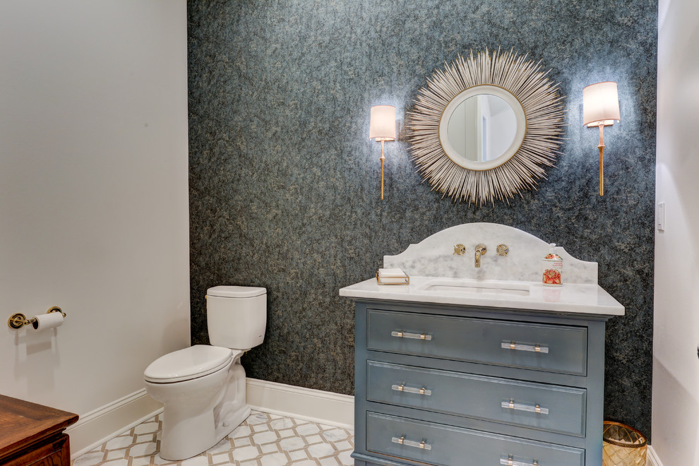 Klassisk inredning av ett vit vitt toalett, med möbel-liknande, blå skåp, en toalettstol med separat cisternkåpa, grå väggar, ett undermonterad handfat och vitt golv