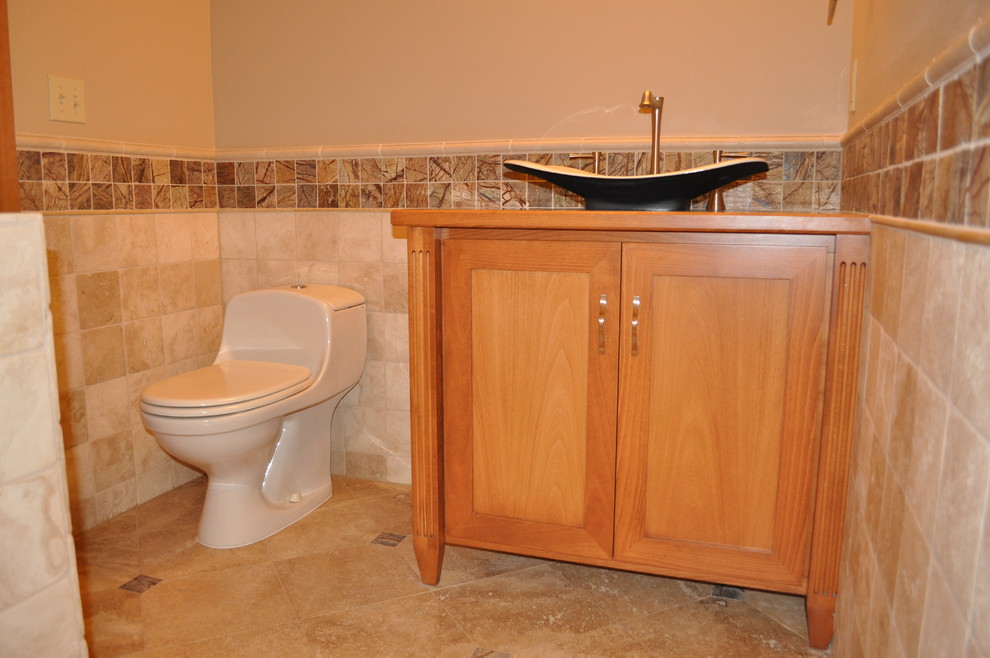 Foto på ett litet amerikanskt toalett, med ett piedestal handfat, luckor med infälld panel, en toalettstol med hel cisternkåpa, beige kakel, porslinskakel, beige väggar, klinkergolv i porslin, marmorbänkskiva och skåp i mellenmörkt trä