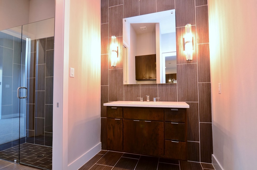 На фото: туалет среднего размера в современном стиле с плоскими фасадами, темными деревянными фасадами, коричневой плиткой, керамогранитной плиткой, бежевыми стенами, полом из керамогранита, врезной раковиной и коричневым полом