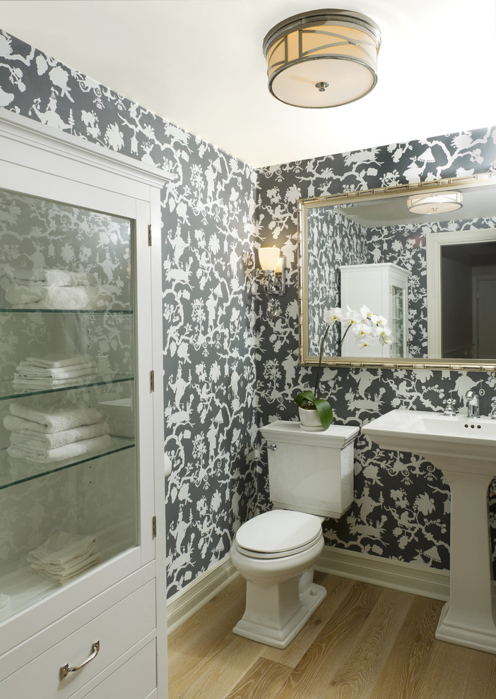 Imagen de aseo clásico de tamaño medio con lavabo con pedestal, puertas de armario blancas, sanitario de dos piezas y suelo de madera clara