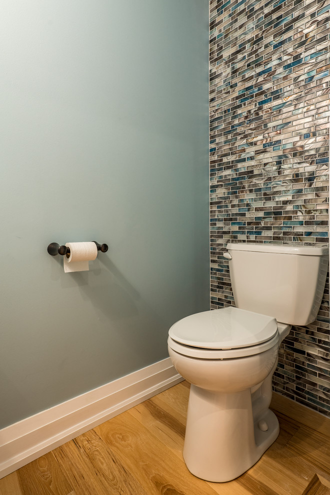 Exempel på ett litet modernt grå grått toalett, med möbel-liknande, vita skåp, en toalettstol med separat cisternkåpa, blå kakel, glasskiva, blå väggar, ljust trägolv, ett nedsänkt handfat, bänkskiva i kvarts och beiget golv