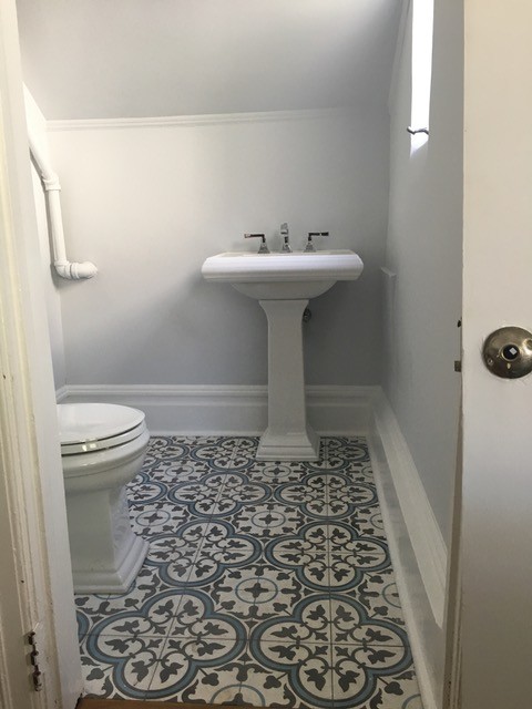 Cette image montre un petit WC et toilettes marin avec WC séparés, un mur gris, carreaux de ciment au sol, un lavabo de ferme et un sol bleu.