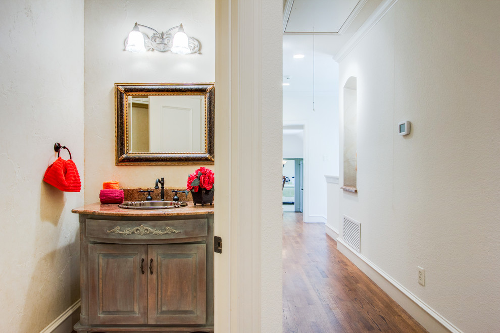 Photo of a small traditional cloakroom in Dallas with freestanding cabinets, distressed cabinets, granite worktops, beige walls and medium hardwood flooring.