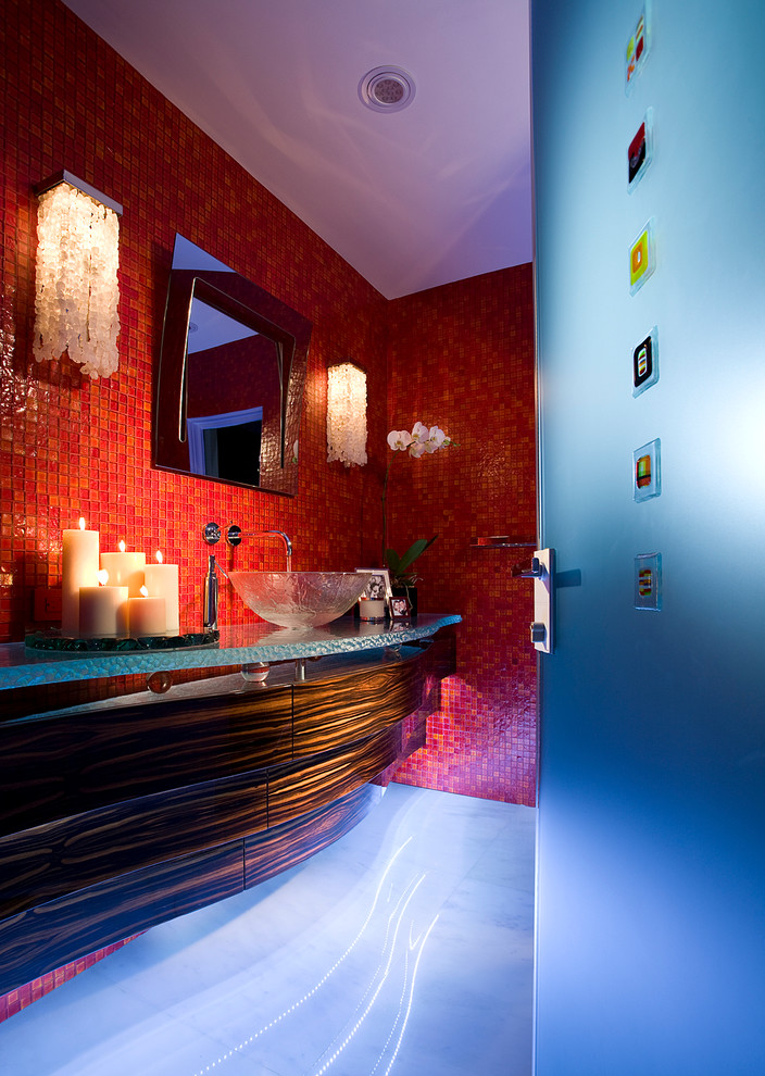 Modern inredning av ett mellanstort toalett, med möbel-liknande, skåp i mörkt trä, en toalettstol med hel cisternkåpa, röd kakel, glaskakel, röda väggar, marmorgolv, ett fristående handfat, bänkskiva i glas och vitt golv