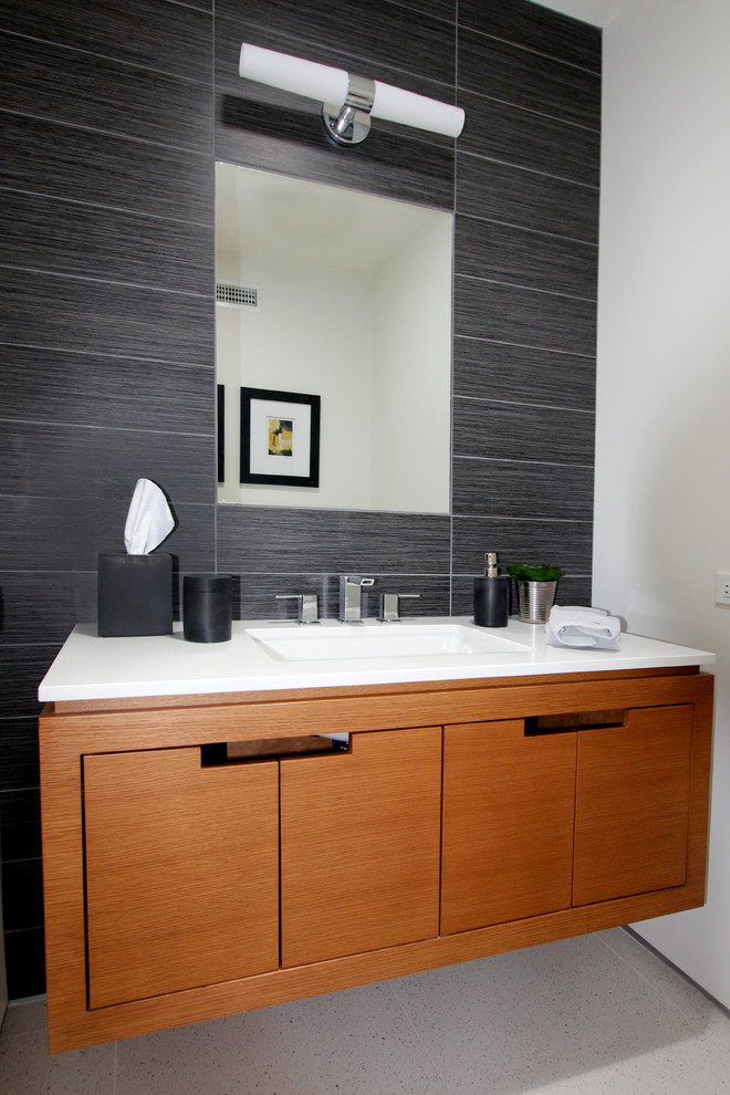 Aménagement d'un WC et toilettes rétro en bois brun de taille moyenne avec un lavabo encastré, un placard à porte plane, un carrelage multicolore, un plan de toilette en quartz modifié, un mur noir et un plan de toilette blanc.